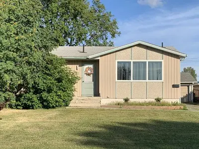 A home with a lawn and trees in front of it.