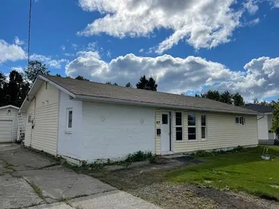 A house in the middle of a yard with a garage.
