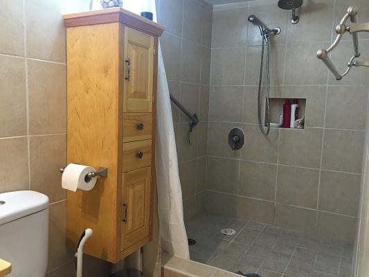 A bathroom with a toilet, sink and shower.