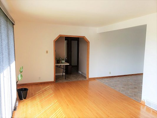 An empty living room with hardwood floors and a window.