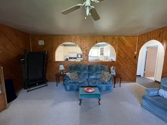 A living room with wood paneling and a ceiling fan.