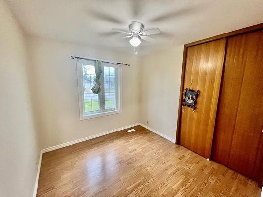 An empty room with hardwood floors and a ceiling fan.