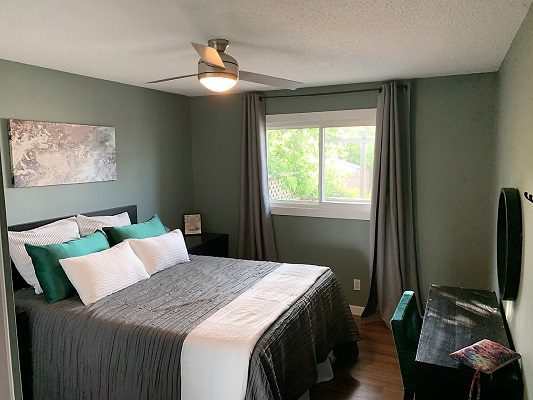 A bedroom with green walls and a ceiling fan.