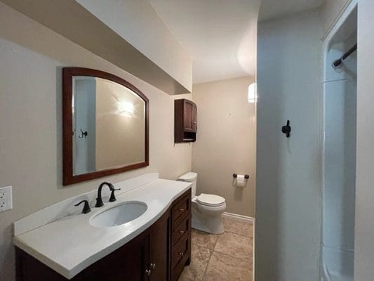 A bathroom with a toilet, sink and mirror.