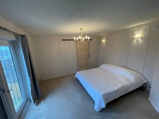 A bedroom with a bed and a chandelier.