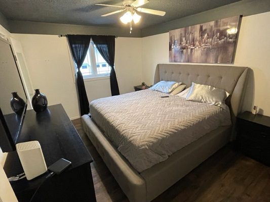 A bedroom with hardwood floors and a ceiling fan.