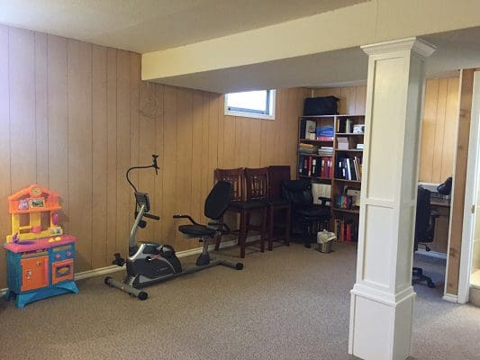 A room with a treadmill, exercise bike, and bookshelf.