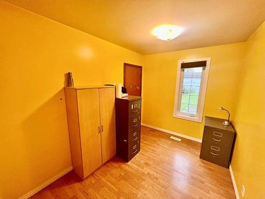 An empty room with yellow walls and wood floors.