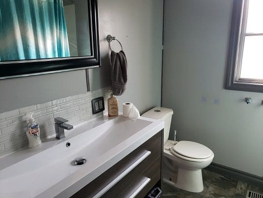A bathroom with a sink, toilet and window.