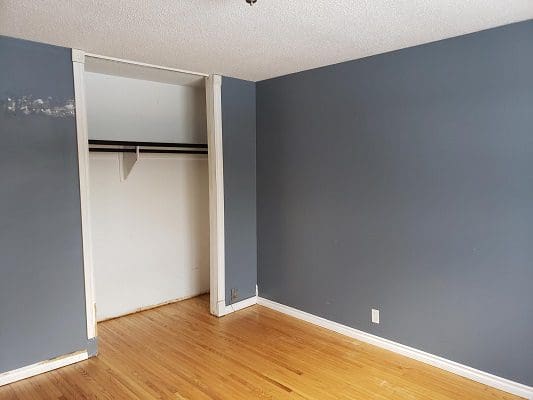 An empty room with blue walls and hardwood floors.