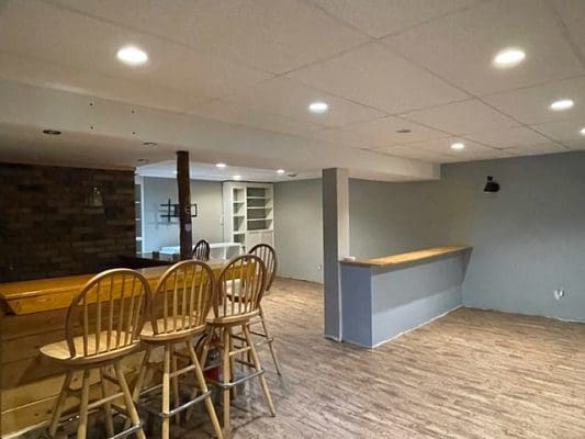 An empty basement with bar stools and wood floors.