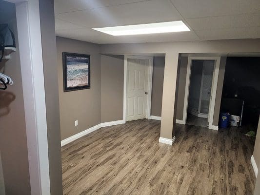 An empty basement with wood floors and a picture on the wall.