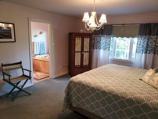A bedroom with a bed and a chair.
