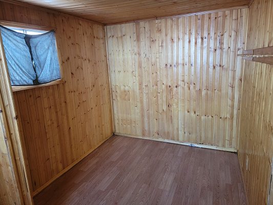 An empty room with wooden walls and a window.