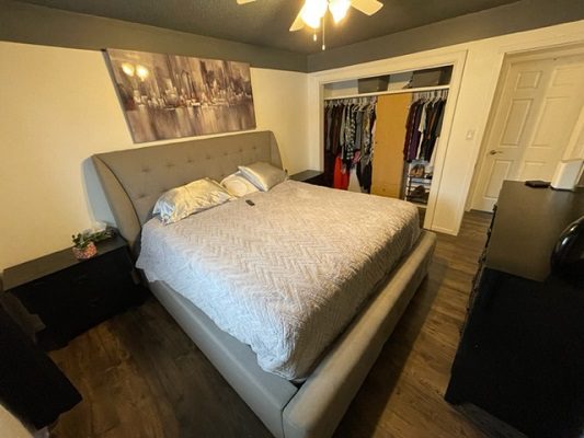 A bedroom with a bed, dresser and closet.