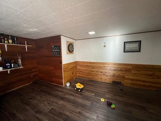 A room with wood paneling and a dart board.