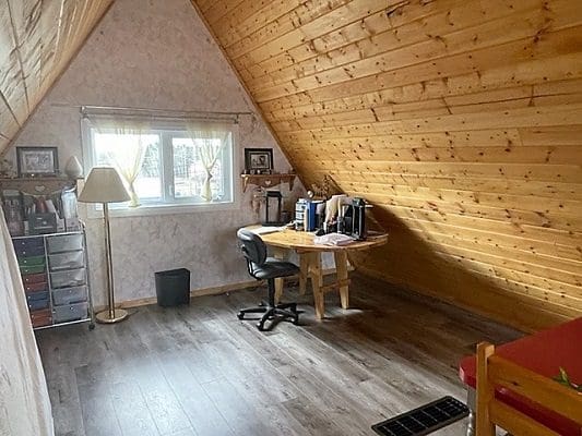 A room in an attic with wood floors and a desk.