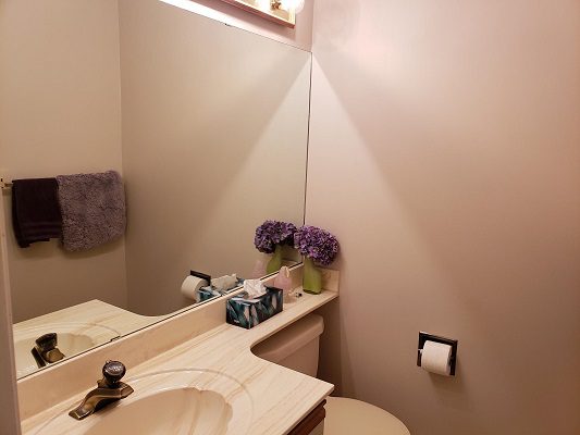 A bathroom with a toilet, sink and mirror.