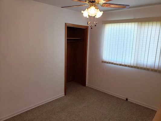 An empty room with a ceiling fan and closet.