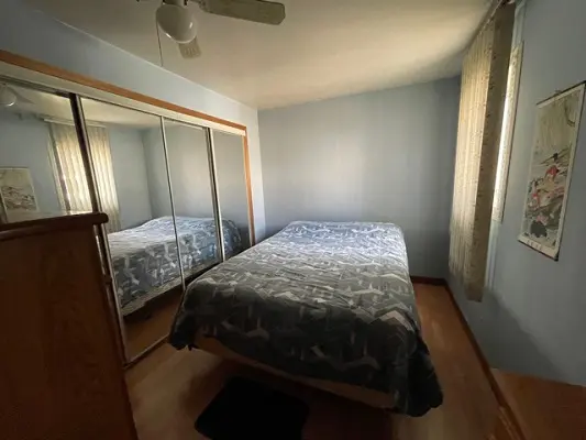 A bedroom with a bed, dresser and mirror.