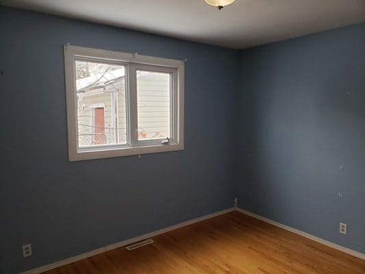 A blue room with hardwood floors and a window.