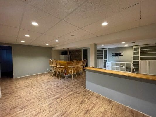 An empty basement with wood floors and a bar.