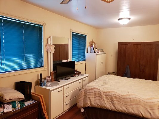 A bedroom with a bed, dresser and tv.