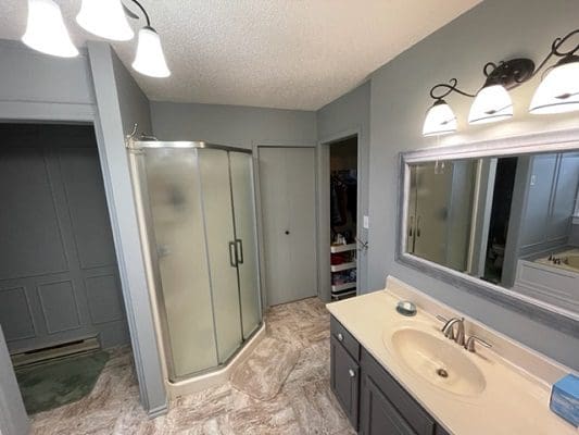 A bathroom with a shower, sink and mirror.