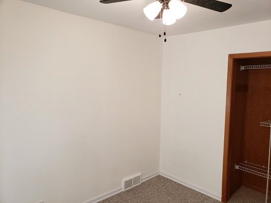 An empty room with a ceiling fan and closet.