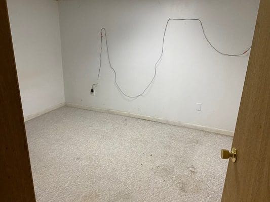 An empty room with wires and a door.