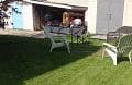 A lawn with lawn chairs and a garage.