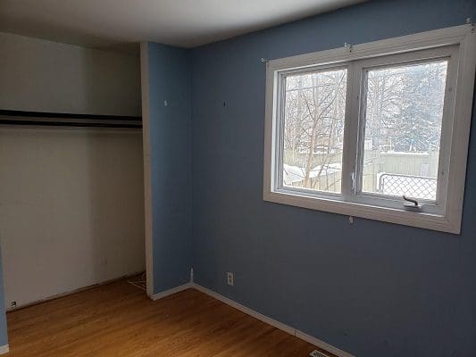 An empty room with blue walls and a window.