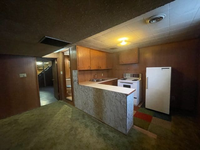 An empty kitchen with a refrigerator and microwave.
