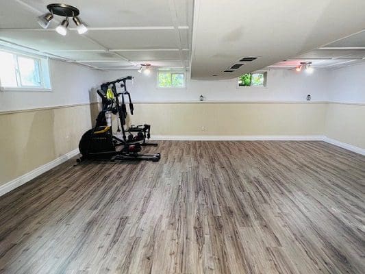 A basement with wood floors and a gym equipment.