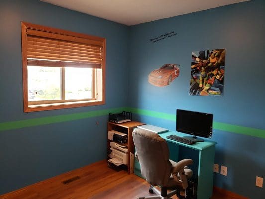 A child's room with blue walls and a desk.