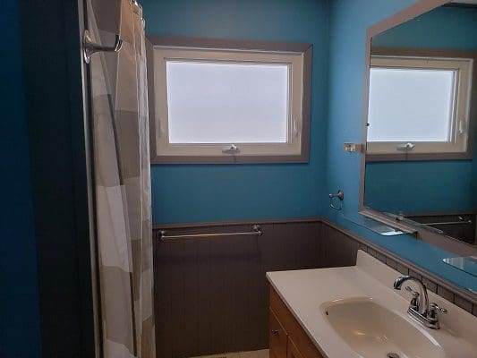A bathroom with blue walls and a window.