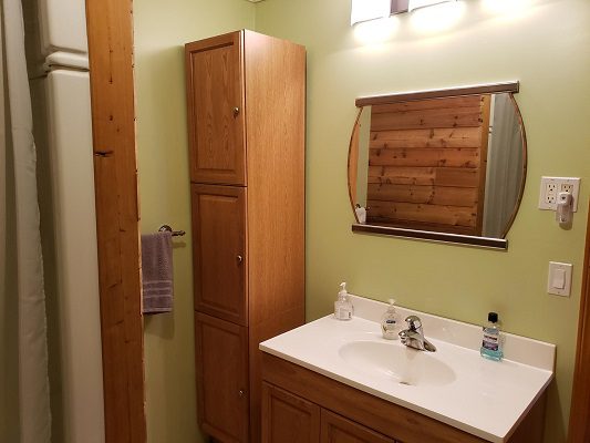 A bathroom with green walls and wooden cabinets.