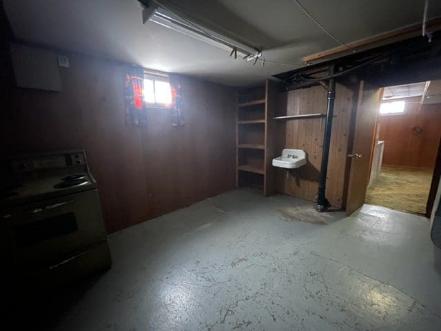 An empty basement with a stove and sink.