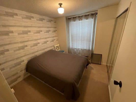 A bedroom with a bed and a bedside table.