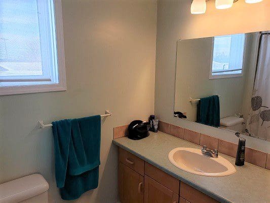 A bathroom with a sink, toilet and a window.