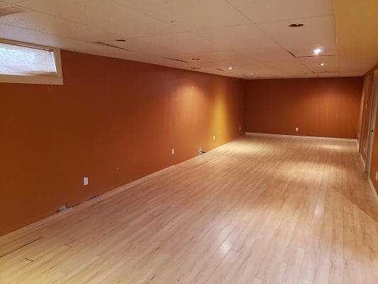 An empty room with orange walls and hardwood floors.