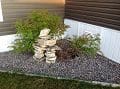 A small rock garden in front of a house.