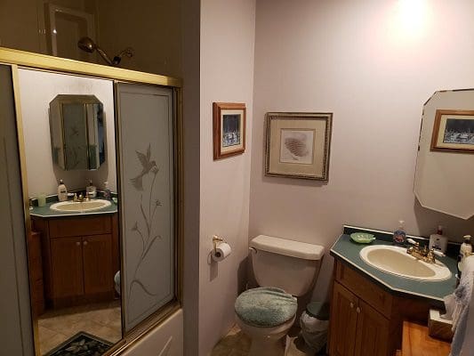 A bathroom with a toilet, sink and mirror.