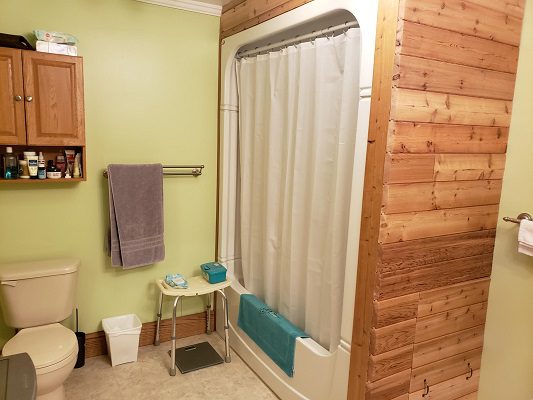 A bathroom with wooden walls and a shower.