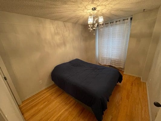 A bedroom with hardwood floors and a blue bed.