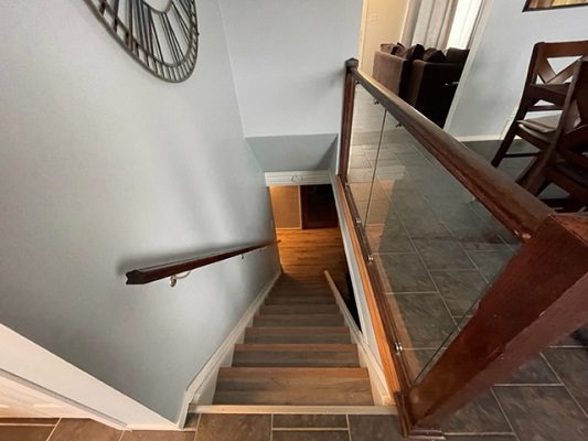 A staircase with a glass railing and a clock.