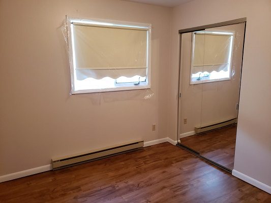 An empty room with hardwood floors and a mirror.