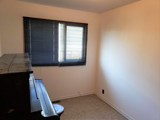 A small room with a piano and a window.