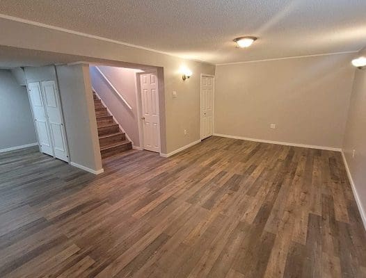 Empty living room with hardwood floors and stairs.