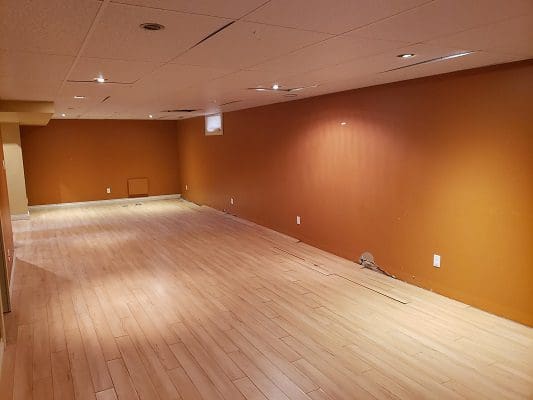 An empty room with orange walls and hardwood floors.